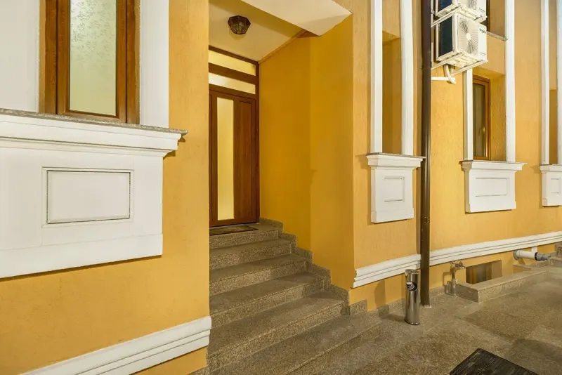 O intrare cu ușă de lemn și trepte de piatră, pe latura casei
